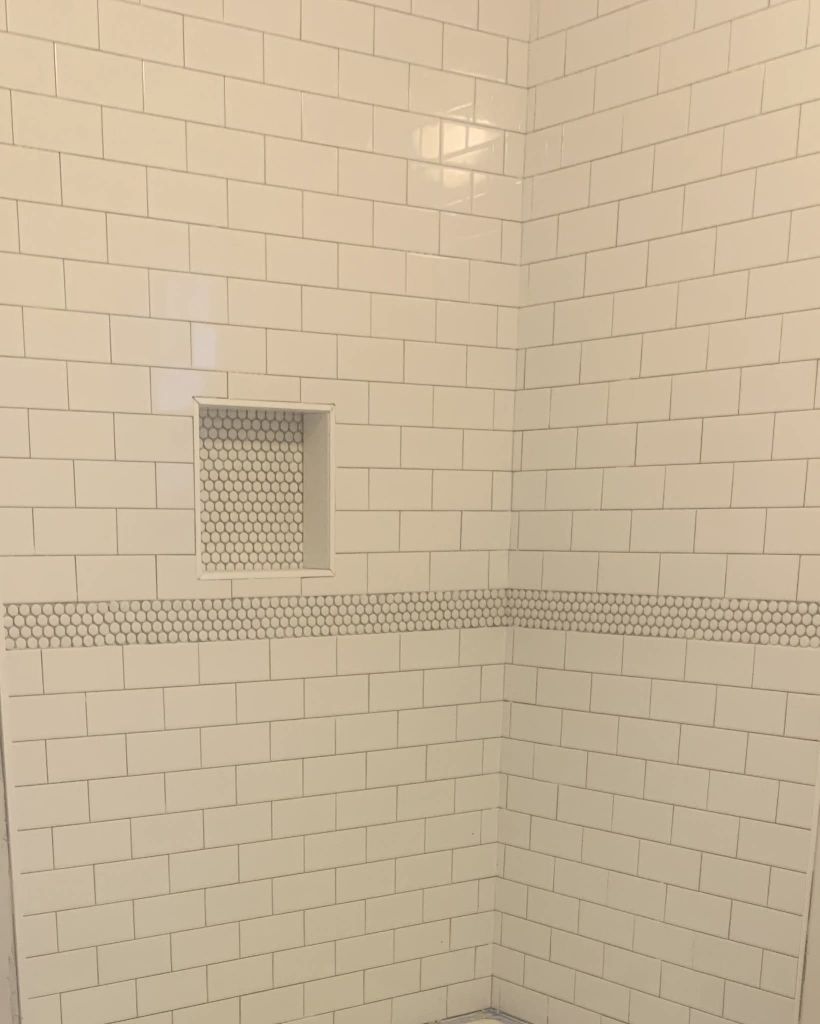 White subway tile shower with penny tile niche accent