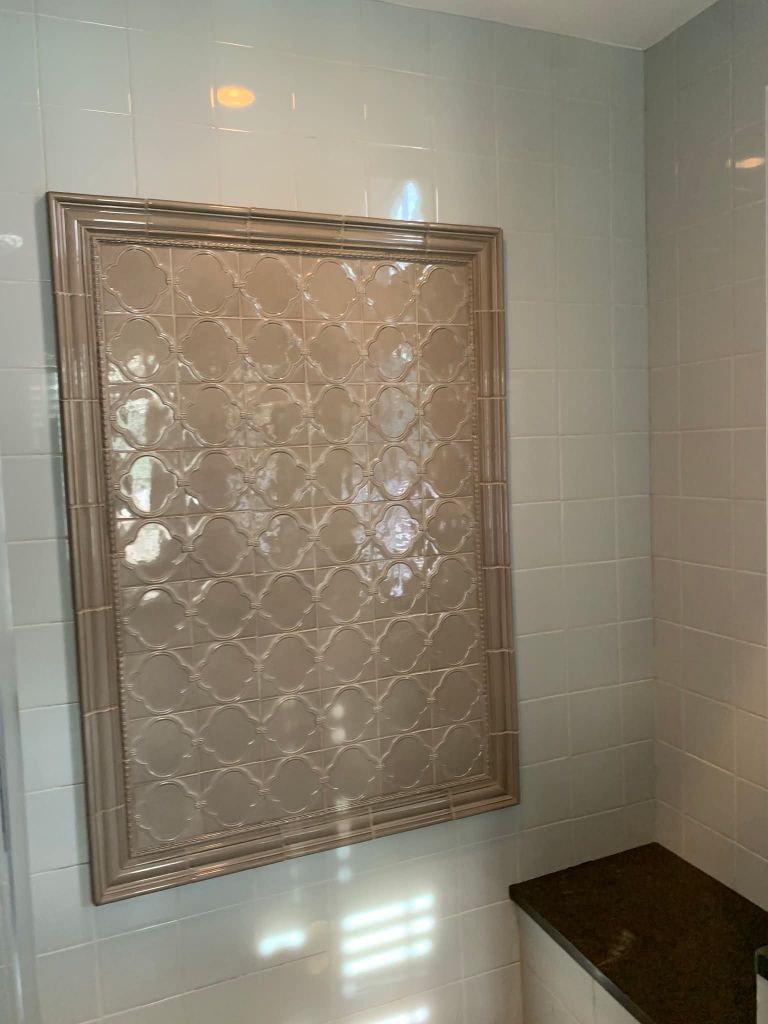 Decorative framed tile accent on bathroom wall
