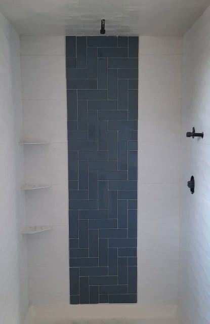 Shower with dark herringbone tile accent panel