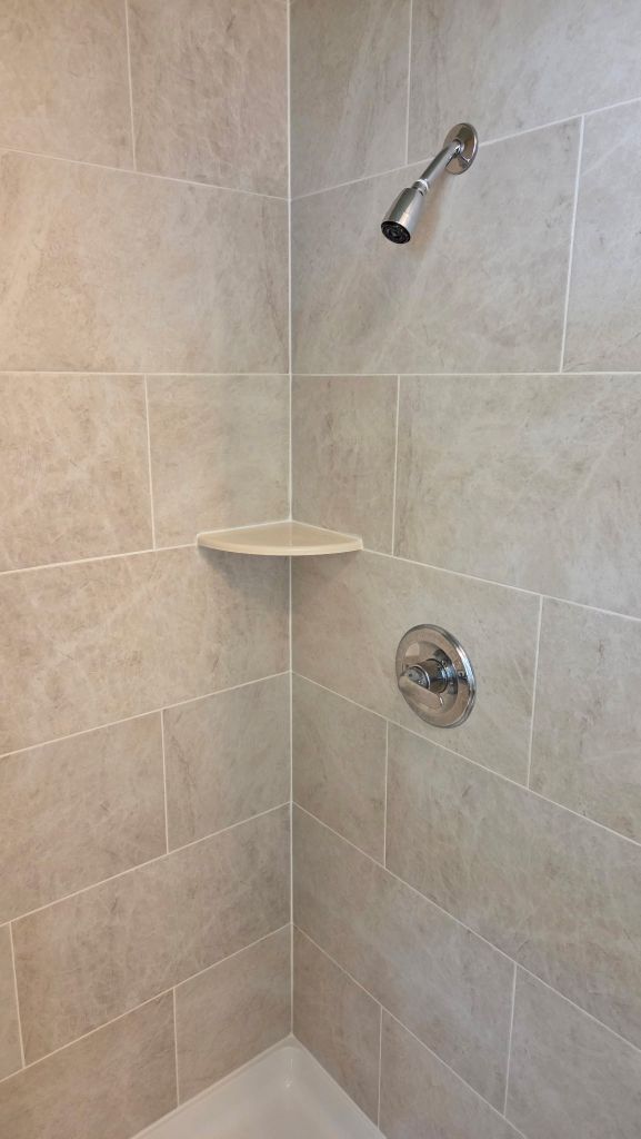 Corner detail of finished tiled shower with fixtures