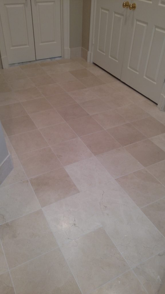 Large-format natural stone tile floor laid in a brick pattern outside bedroom closet doors