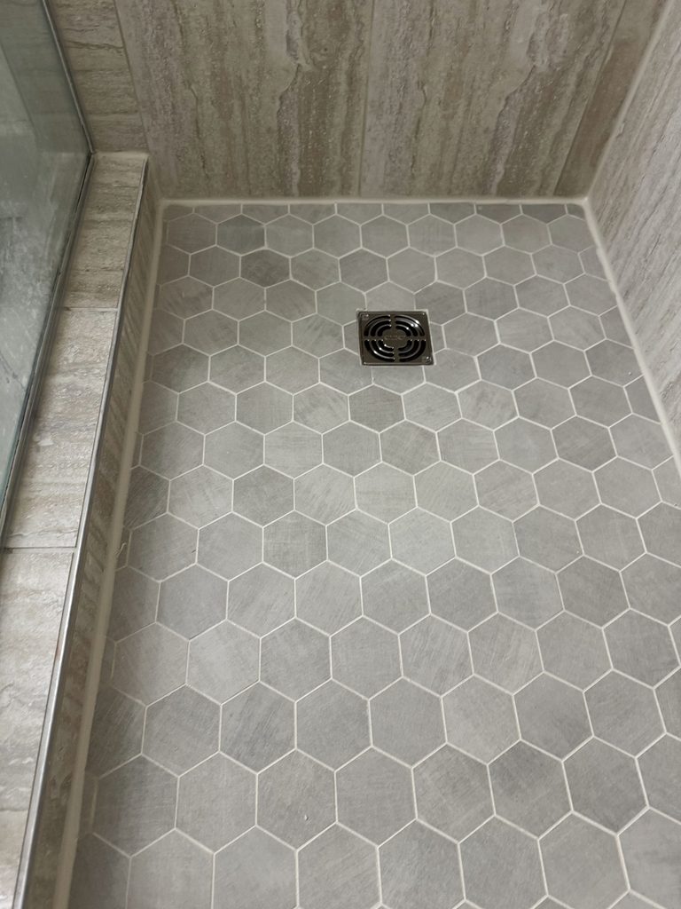 Shower with gray hexagon mosaic floor tile and wood-look plank wall tile