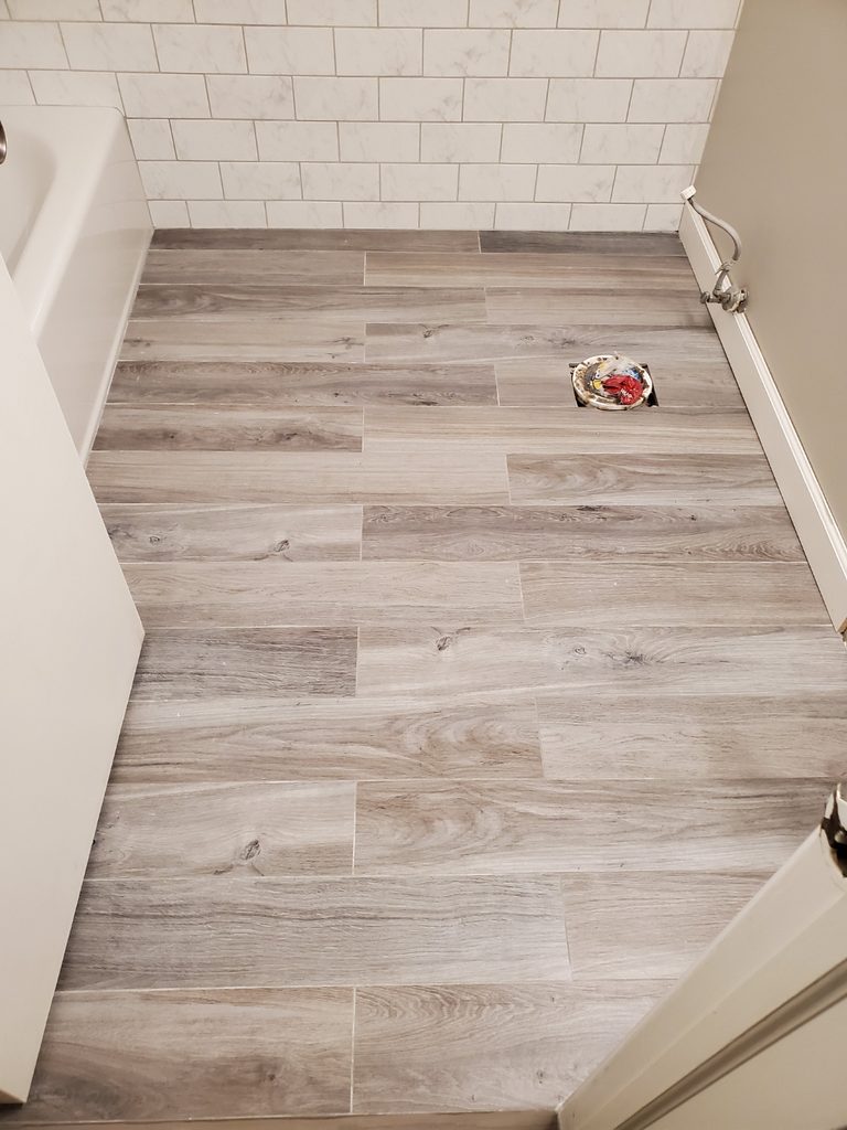 Wood-look plank tile bathroom floor paired with marble subway tile tub surround